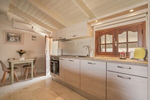 Een moderne keuken met houten kastjes, een inbouwoven en een eethoek met een tafel en stoelen.