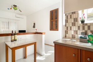 Uma cozinha com uma mesa de madeira, uma janela com vista e um armário com escorredor de louça.