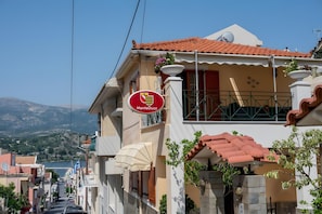 A building with a balcony, a sign reading 'MonteDuca,' and a view of a street and mountains in the background.