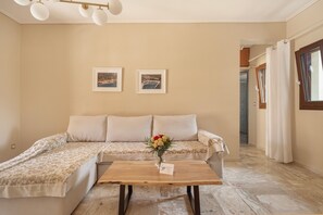 Quarto com sofá, mesa de madeira e duas imagens emolduradas na parede.