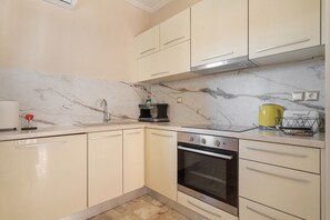 Cozinha com painel de parede de mármore, eletrodomésticos de aço inoxidável e armários de cor clara.