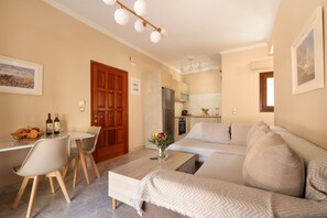 Uma sala moderna com sofá, mesa de jantar com cadeiras, área de cozinha e porta de madeira.