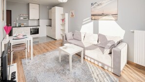 A modern living room with a sofa, coffee table, and a dining area with a table set for two. - Warszawa-Włochy Serene Apartment (Warszawa)