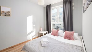 A modern bedroom with a large bed, a bedside table, a hanging light, and a window with curtains. - Warszawa-Włochy Serene Apartment (Warszawa)