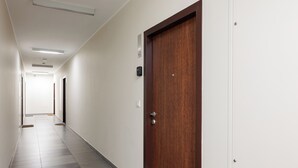 A corridor with a wooden door, white walls, and a tiled floor. - Warszawa-Włochy Serene Apartment (Warszawa)