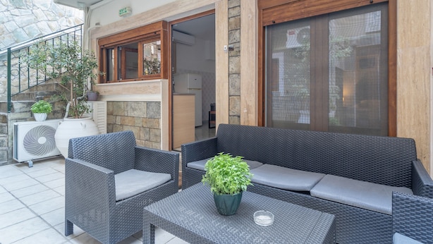 An outdoor seating area with wicker furniture, a potted plant, and a stone wall. - Studio 'Ainos' with Private Terrace, Wi-Fi and Air Conditioning (Argostoli)