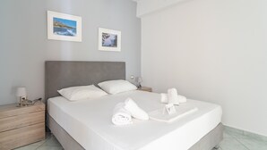 A neatly made bed with white linens, a grey headboard, and a bedside table with a lamp. Two framed pictures are hung on the wall above the bed. - Studio 'Ainos' with Private Terrace, Wi-Fi and Air Conditioning (Argostoli)