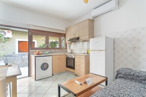 Una cocina compacta con lavadora, un comedor con mesa, y un sofá.