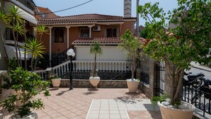A residential building with a tiled patio, potted plants, and a staircase leading to a balcony. - Studio 'Ainos' with Private Terrace, Wi-Fi and Air Conditioning (Argostoli)