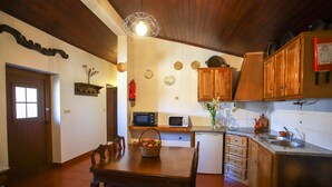 Una cocina con armarios de madera, un microondas, un lavamanos y una mesa de comedor con sillas.