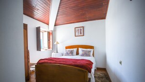 Un dormitorio con una cama de madera, una mesita de noche, una lámpara y un cuadro en la pared.