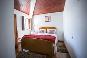 A bedroom with a wooden bed, a nightstand, a lamp, and a framed picture on the wall.