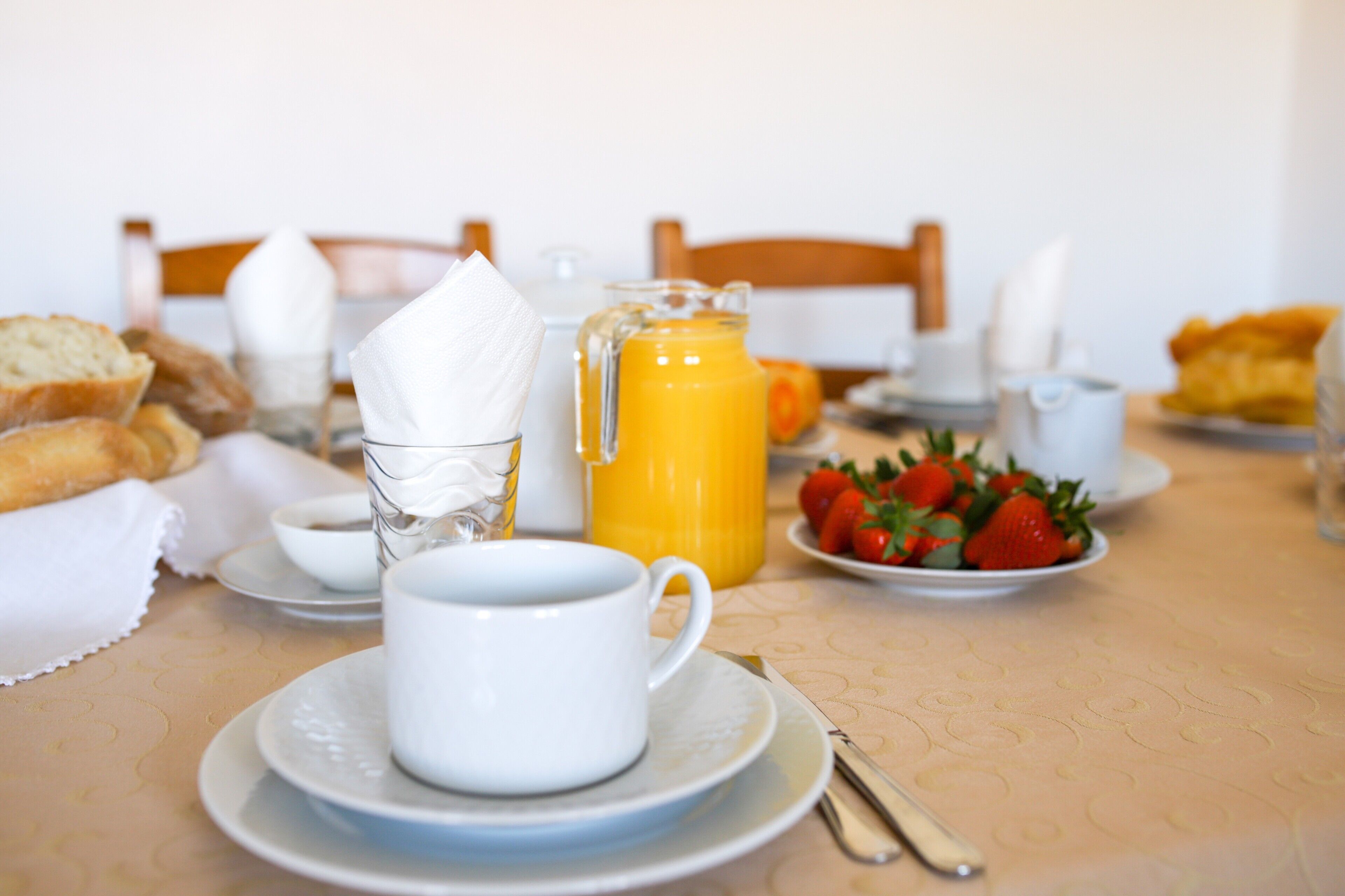 A breakfast table with a cup, jug, and plates of food.