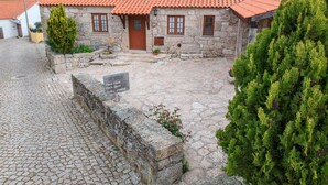 Un edificio de piedra con tejado de tejas rojas, un patio empedrado y un letrero que indica que es una casa de huéspedes.