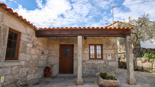 Un edificio de piedra con techo de tejas, puerta de madera y una pequeña ventana.