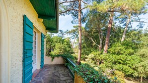 A stone pathway leading to a building with green shutters and a wooden fence. - Villa Eole – Elegant villa with garden in Hossegor, steps from the beach and town center (Soorts-Hossegor)