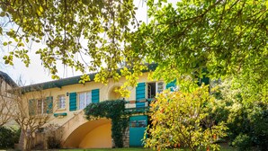 A building with a yellow facade, green shutters, and an arched entrance. - Villa Eole – Elegant villa with garden in Hossegor, steps from the beach and town center (Soorts-Hossegor)