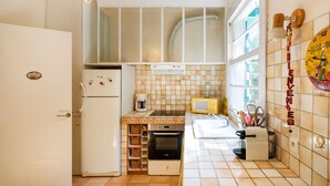 A compact kitchen with a refrigerator, oven, microwave, and a sink. - Villa Eole – Elegant villa with garden in Hossegor, steps from the beach and town center (Soorts-Hossegor)