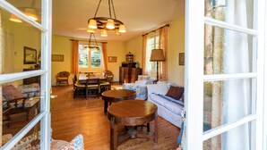 A cozy living room with a sofa, chairs, a dining table, and a wooden floor. - Villa Eole – Elegant villa with garden in Hossegor, steps from the beach and town center (Soorts-Hossegor)