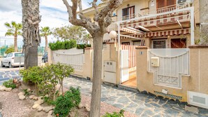 A two-story building with a balcony, a gated entrance, and a stone-paved driveway. - Bungalow 'Casa De Verónica' with Private Terrace, Wi-Fi and Air Conditioning (Santa Pola)
