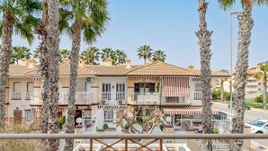 A row of Mediterranean-style buildings with balconies, palm trees, and a clear sky. - Bungalow 'Casa De Verónica' with Private Terrace, Wi-Fi and Air Conditioning (Santa Pola)