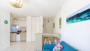 A modern kitchen with white cabinets, a granite countertop, and a small island with stools.