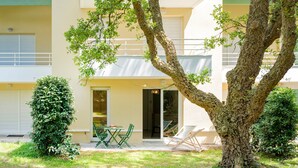 A building with a balcony, a tree, and a patio with a table and chairs.