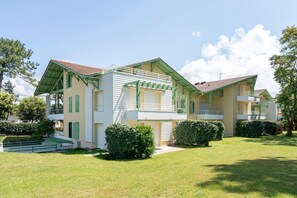 A two-story building with a balcony, a covered porch, and a well-maintained lawn.