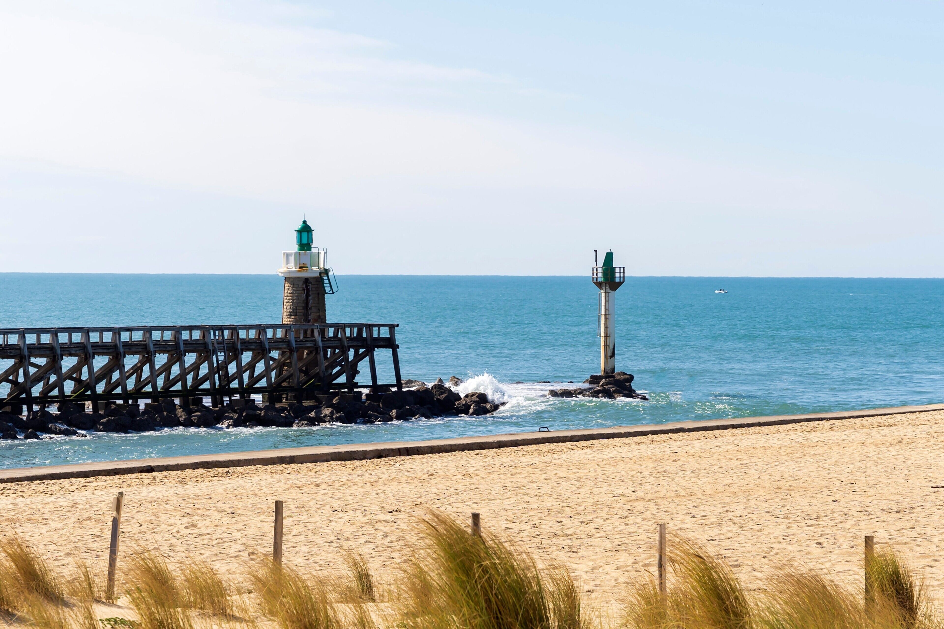 A beach with a wooden pier and two lighthouses.