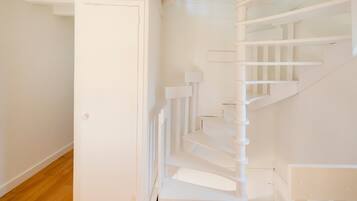 A white staircase with a wooden floor, a white door, and a white wall.