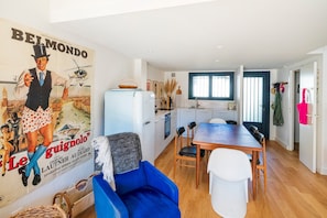 A modern kitchen with a refrigerator, dining table, and chairs.