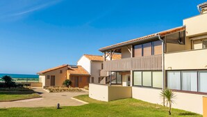 Un bâtiment moderne doté d’un toit plat, de grandes fenêtres et d’une cour dallée.