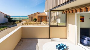 Un balcon avec une table, des chaises et une vue sur la plage et les autres bâtiments.