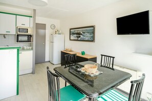 Une cuisine de taille réduite avec une table à manger, des chaises, un téléviseur et un tableau accroché au mur.