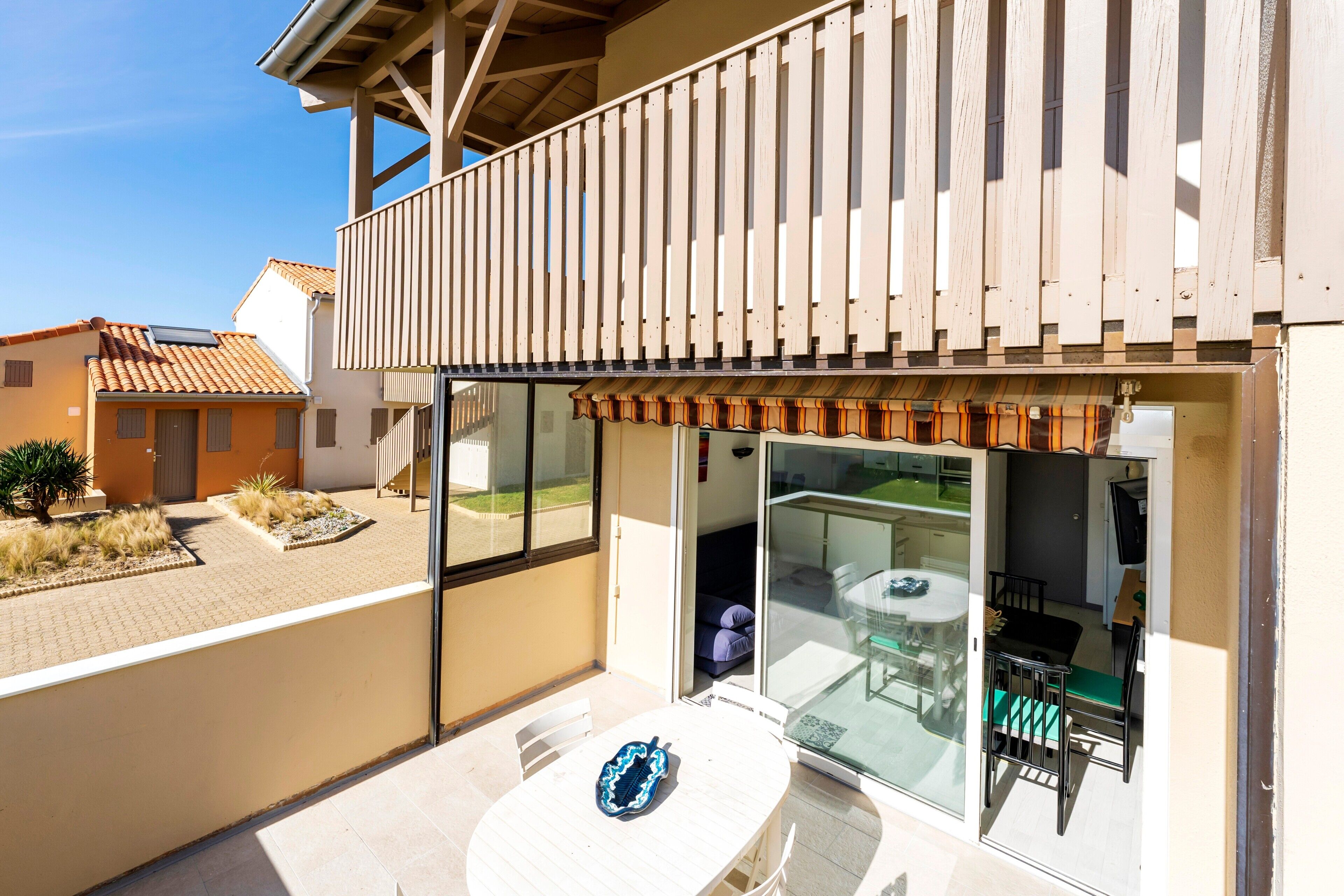 Eine moderne Außenpatio mit Glastür zum Balkon, einem weißen Tisch und einem Stuhl.