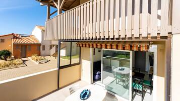 Eine moderne Außenpatio mit Glastür zum Balkon, einem weißen Tisch und einem Stuhl.