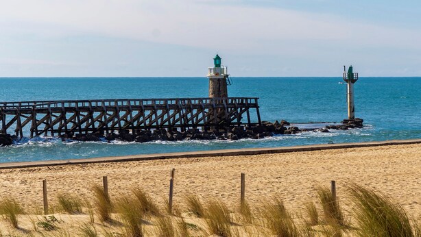 Une jetée qui s’avance dans l’océan, avec un phare à son extrémité.
