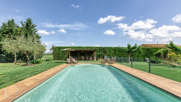 A rectangular swimming pool with a tiled edge, surrounded by a grassy area and a fence. - Country House 'Can Planas 1' with Shared Pool, Wi-Fi and Air Conditioning (Fonolleres)