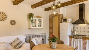 A cozy kitchen with a wooden table, chairs, a white cabinet, and a brick wall. - Country House 'Can Planas 1' with Shared Pool, Wi-Fi and Air Conditioning (Fonolleres)