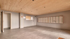 Una habitación con techo de madera, paredes grises y suelo de baldosas. Se observa un mueble de almacenamiento fijado a la pared con varios compartimentos.
