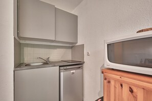 Eine kleine Küche mit integriertem Geschirrspüler, Mikrowelle und Holzschrank.
