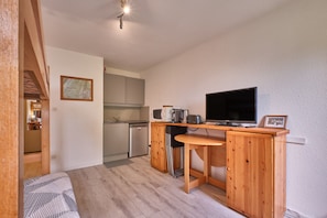 A compact kitchen with a wooden table, a television, and a microwave. - Apartment 'Prapoutel Pied Des Pistes' with Mountain View and Balcony (Les Adrets)