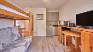 Habitación pequeña con literas, kitchenette y televisor.