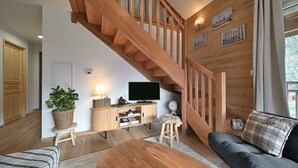 Een houten trap, een televisie, een plant en een bank in een woonkamer.