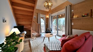 Een houten interieur met een bank, een tafel, een televisie en een trap.