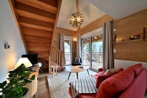Un interior de madera con un sofá, una mesa, un televisor y una escalera.