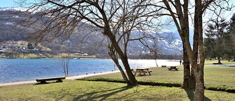 A park with benches, a picnic table, and a lake with mountains in the background.