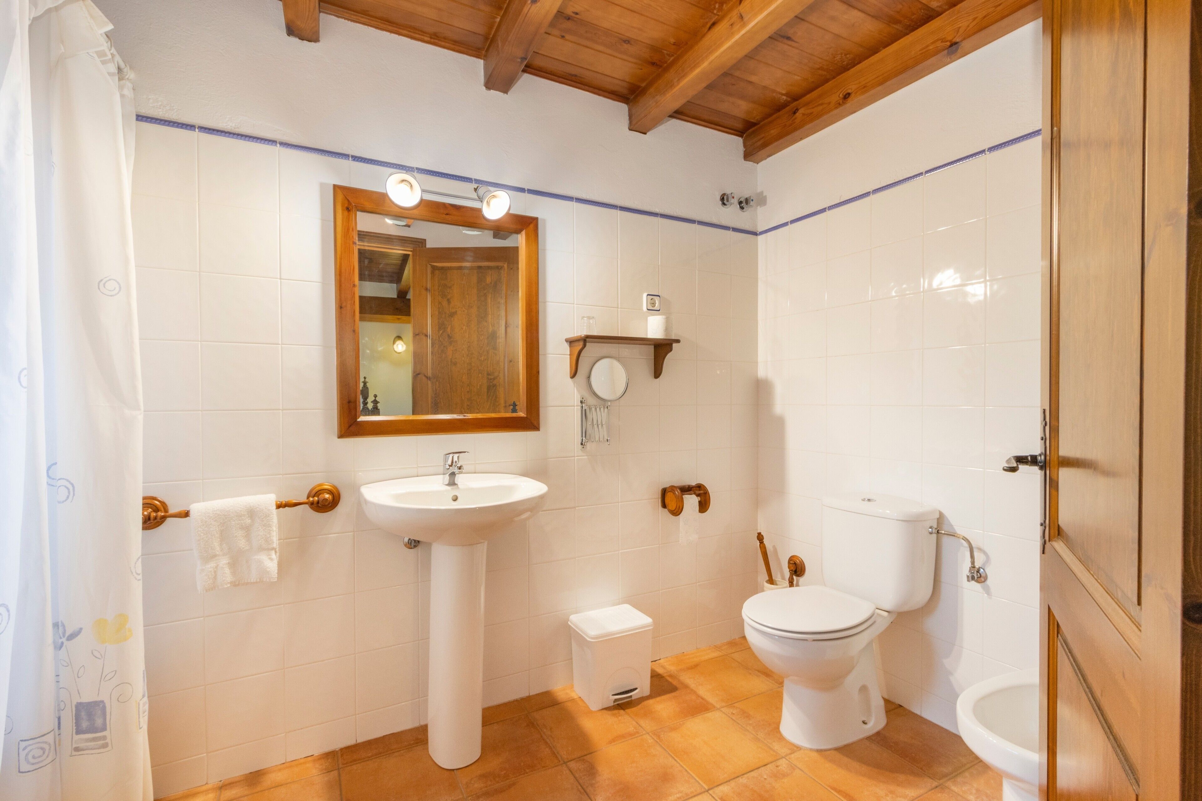 Een badkamer met een wastafel, spiegel, toilet en douchegordijn.