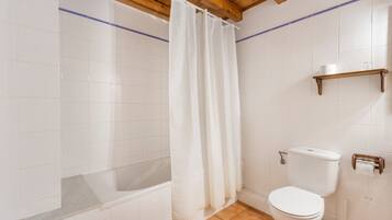 Un baño con bañera, inodoro y cortina de ducha.