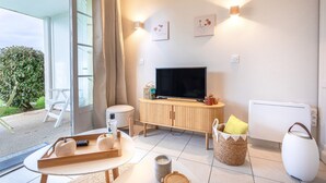 Una sala de estar moderna con televisor, mueble de madera y vistas al verdor exterior.